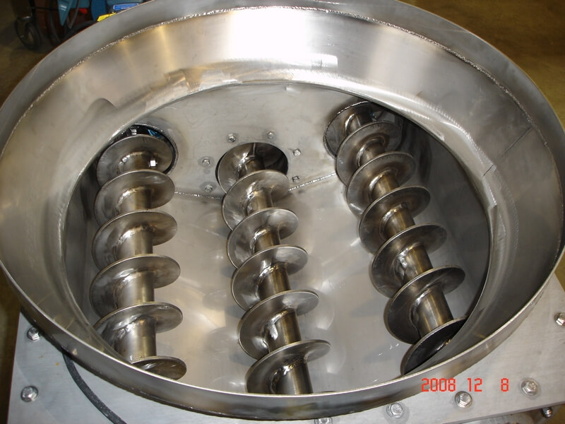 Three screws inside a stainless steel tri-screw feeder bowl for PVC pellets