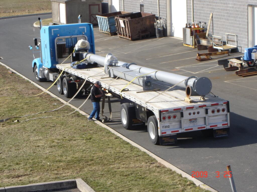 Long screw conveyor loaded on a flatbed truck for shipment